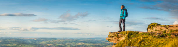 female hiker looking out over idyllic landscape from mountain top