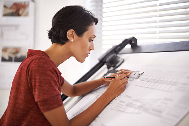 Paying attention to the finer details Shot of an attractive young architect working in her office architect stock pictures, royalty-free photos & images