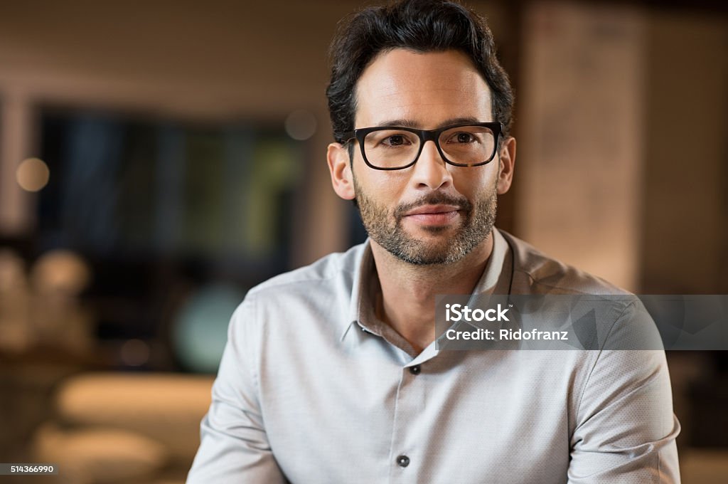 Positive businessman Portrait of a young handsome businessman wearing glasses. Close up of smiling business man wearing eyeglasses. Thinking business man wearing glasses sitting in office. Men Stock Photo