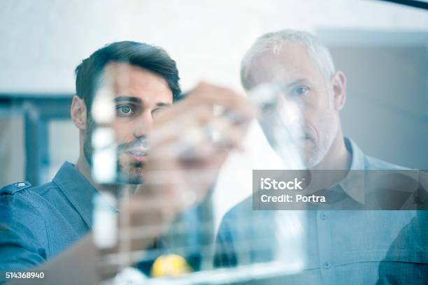 Businessmen Making Plan On Glass Wall In Office Stock Photo - Download Image Now - Business, Leadership, Manager
