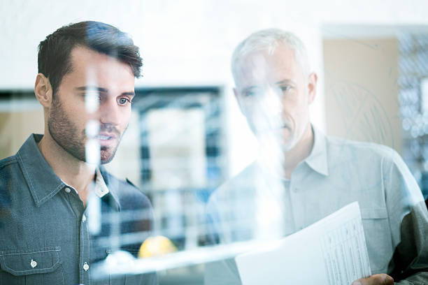 istock Businessmen analysing plan on glass wall 514369160