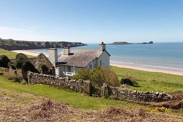 Cottage on the Beach Swansea, UK: May 02, 2013: The Rectory is a National Trust rental cottage that overlooks Rhossili Bay. It is in high demand through the summer months and was built in the 1850's.  rhossili bay stock pictures, royalty-free photos & images