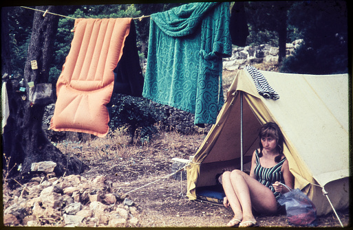 Original vintage colour slide from 1960s, young woman sitting in a tent.