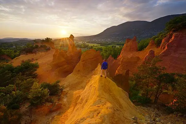 Hiker in Colorado Provençal observes a magnificent sunset, Rustrel, Provence, France