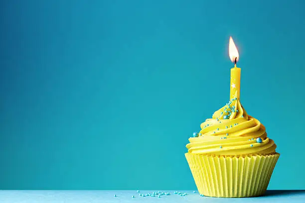 Yellow birthday cupcake on blue
