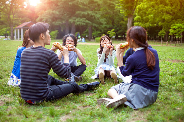 heureux groupe d'amis japonais repas dans le parc tokyo - coffee to go flash photos et images de collection