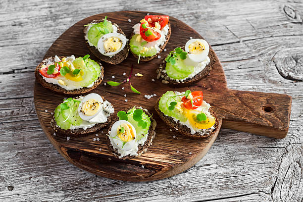 Sandwiches with soft cheese, quail eggs, cherry tomatoes and celery Sandwiches with soft cheese, quail eggs, cherry tomatoes and celery. Delicious healthy snack or breakfast egg cherry tomato rye stock pictures, royalty-free photos & images