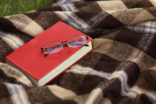 Book and glasses on the plaid, reading, education - concept