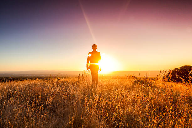 a man striding through the desert meadow with a suit on at the intersection of business and the environment.  horizontal composition with copy space and filtered color treatment.