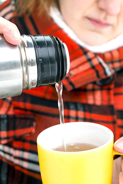 istock Pouring Hot Tea from Thermos Bottle to Yellow Cup 514382500