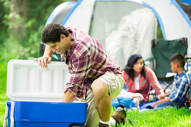 famille de quatre personnes plein air dans la tente de camping en forêt et des fournitures de bureau. - glacière photos et images de collection