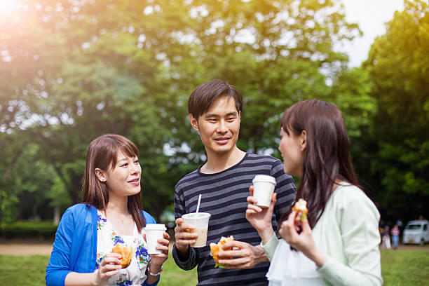 heureux groupe d'amis japonais repas dans le parc tokyo - coffee to go flash photos et images de collection