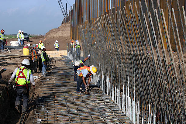Border Wall, Rio Grande Valley, Texas, Aug., 2008 Granjeno, Texas, USA - August 15, 2008:  Construction workers erect a border wall ordered by the Department of Homeland Security to deter illegal immigrants from entering the U.S. just north of the Rio Grande River in the Rio Grande Valley in deep south Texas.  The effectiveness of the wall is a matter of dispute, as immigrants continue to enter illegally on a daily basis. international border barrier stock pictures, royalty-free photos & images