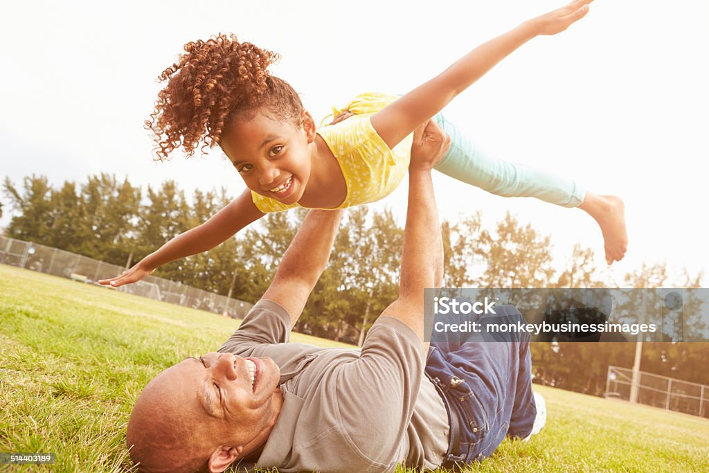 Grandfather Playing Game With Granddaughter In Park Grandfather Playing Game With Granddaughter In Park Smiling To Camera Grandparent Stock Photo