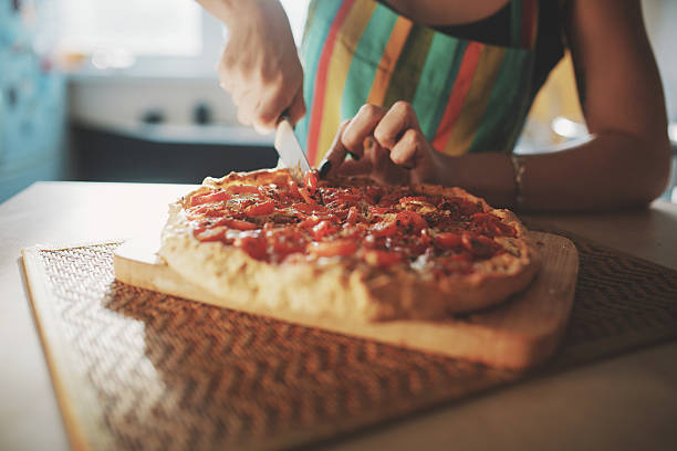 istock Young woman with a knife cut the pizza 514404812