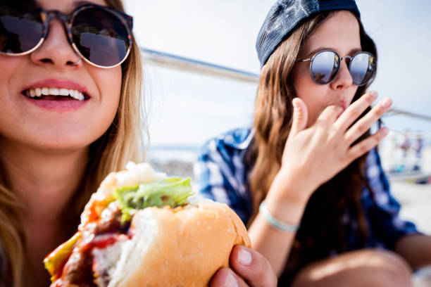 giovani ragazza hipster gli amici indossando occhiali da sole, mangia hamburger t - food people close up outdoors foto e immagini stock