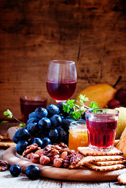 Plate with appetizers guilt: black grapes, cheese, crackers, pears, nuts, honey, almonds, on a dark wooden background, selective focus
