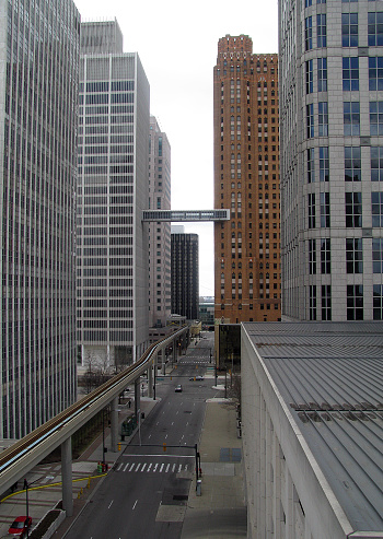 In Detroit, two tall buildings are connected by an enclosed pedestrian walkway hanging above the city street and PeopleMover monorail track below.
