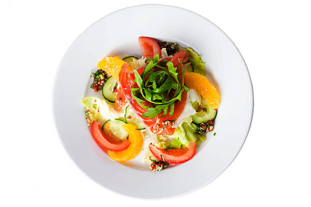 salad with red fish, tomatoes, cucumbers and oranges on a white background
