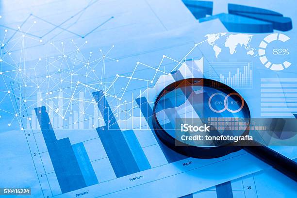 Magnifying Glass And Documents With Analytics Data Lying On Tabl Stock Photo - Download Image Now