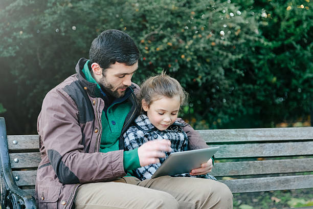 istock Father and daughter with a tablet in a park 514420921