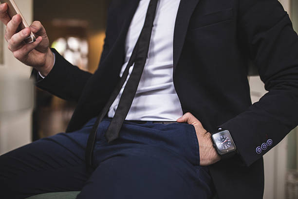 cerrar de hombre con el torso;  traje;  corbata smartwatch y teléfono inteligente - airport newspaper travel business travel fotografías e imágenes de stock