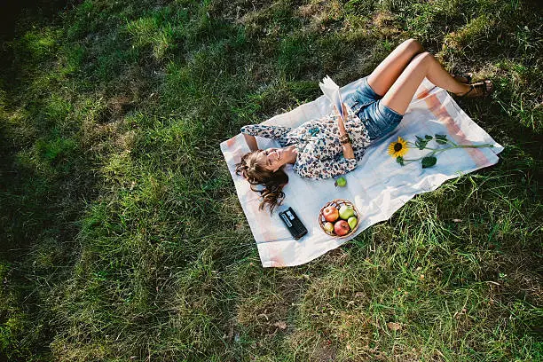 Photo of Happy girl lying and reading in a park