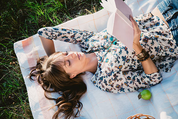Girl lying in the park and reading stock photo