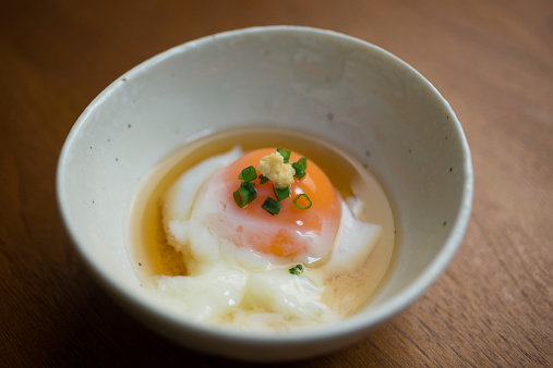 Onsen tamago (温泉卵 or 温泉玉子) is a traditional Japanese low temperature egg which is originally slow cooked in the water of onsen hot springs in Japan. The egg has a unique texture that the white tastes like a delicate custard (milky and soft) and the yolk comes out firm, but retains the color and creamy texture of an uncooked yolk. The special texture is cooked by using the difference between the temperature of which the egg yolk and egg white solidifies. The egg is poached within the shell and is served with the shell removed in a small cup with sauce of broth and soy sauce.