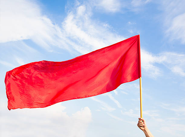 istock Hand waving a red flag with blue sky background 514440551