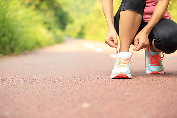 istock woman runner tying shoelaces on trail 514442795