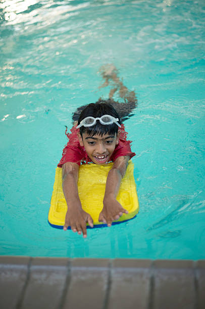 istock Boy is swimming with a floading board in a pool 514452114