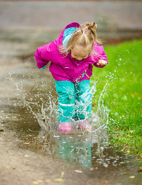 istock Happy little girl plays in a puddle 514454239