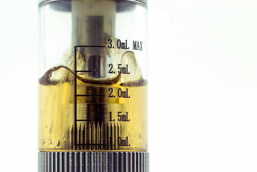 An e-cigarette tank with the mL measurements filled with juice.