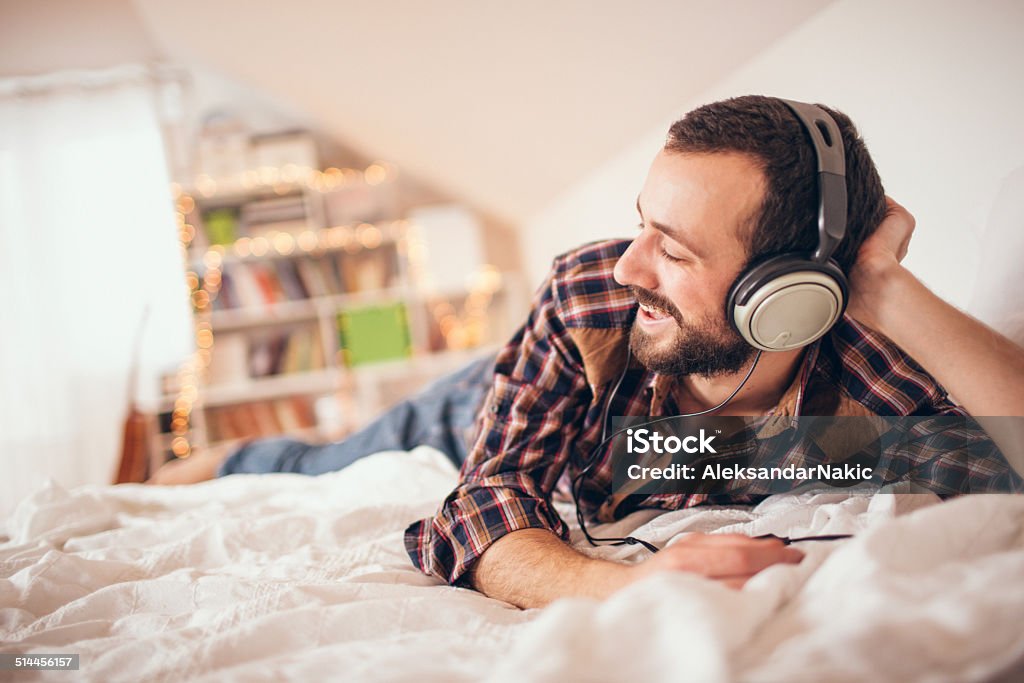 Listening music Young man listening music in his room Adult Stock Photo