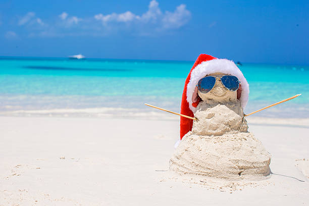 istock Sandy snowman with red Santa Hat on white Caribbean beach 514457337