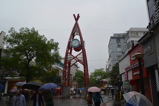 Guilin, China - April 24, 2014: people protecting from the rain with umbrellas sightseeing the popular walking street in Guilin, a promenade with many shops and bars.