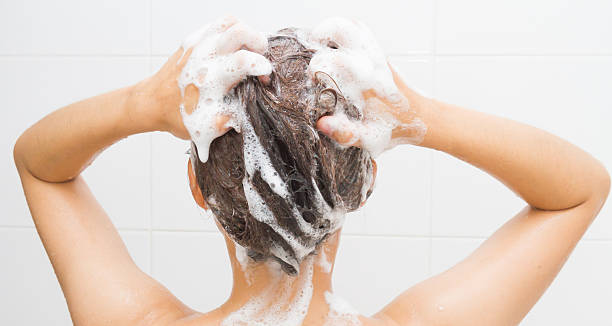 Woman washing her hair Woman washing her hair on white tiles background. shampoo stock pictures, royalty-free photos & images