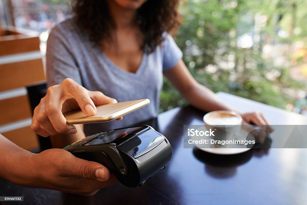 NFS technology Woman using NFC technology when paying in restaurant Paying Stock Photo