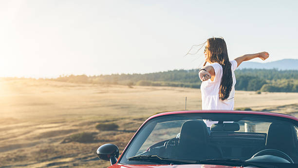 happy asian woman standing in car with arms raised happy asian woman standing in car with arms raised, San Juan Island, WA, USA. happy car asian stock pictures, royalty-free photos & images