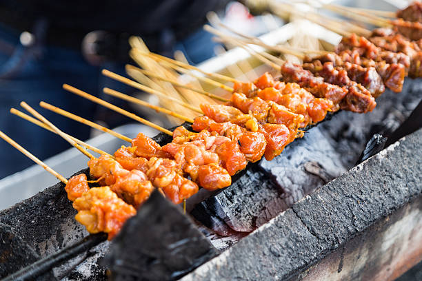 istock Vendor preparing chicken and beef barbecue satay on charcoal gri 514463412