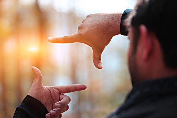 Man hands framing distant sun rays. 