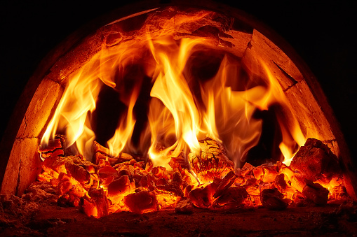 Firewood burning in fire. Flame in furnace. Hearth in house. Fireplace details. Yellow light.