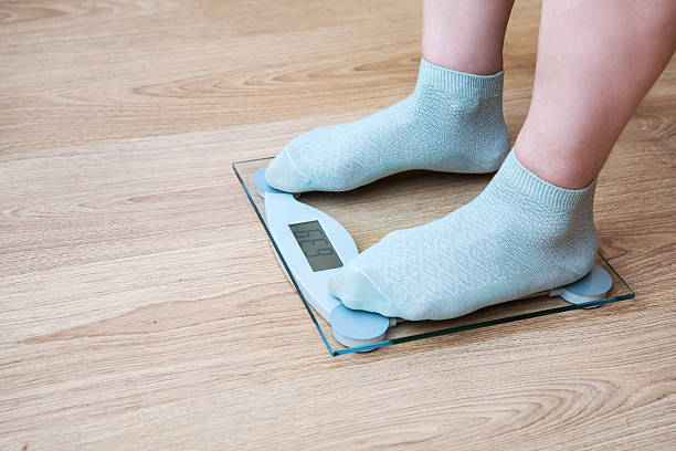 istock woman's legs standing on the scales 514469176