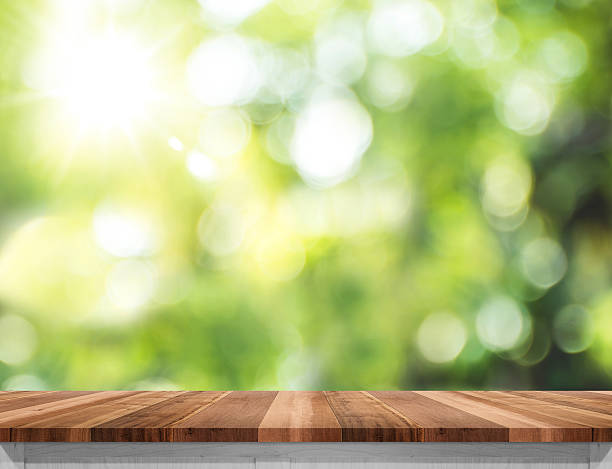 Empty wood table top with sun and blur green tree