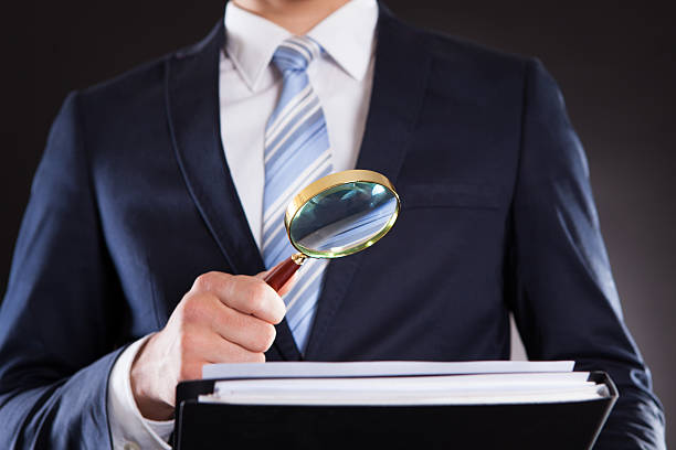 istock Businessman Examining Documents With Magnifying Glass 514476417