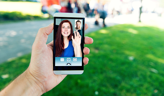 Man and woman is talking to each other thorugh a video call on a smartphone.