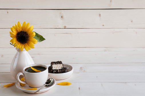 sunflower and a cup of coffee on a wooden background