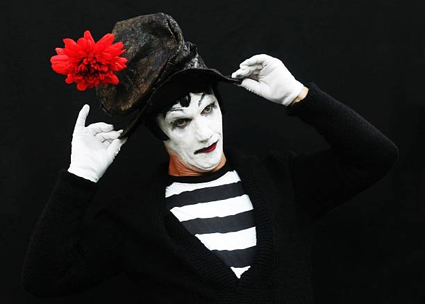 mime artist against black background adjusting his hat