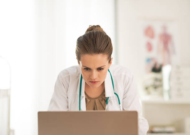 istock concerned doctor woman looking in laptop 514497996